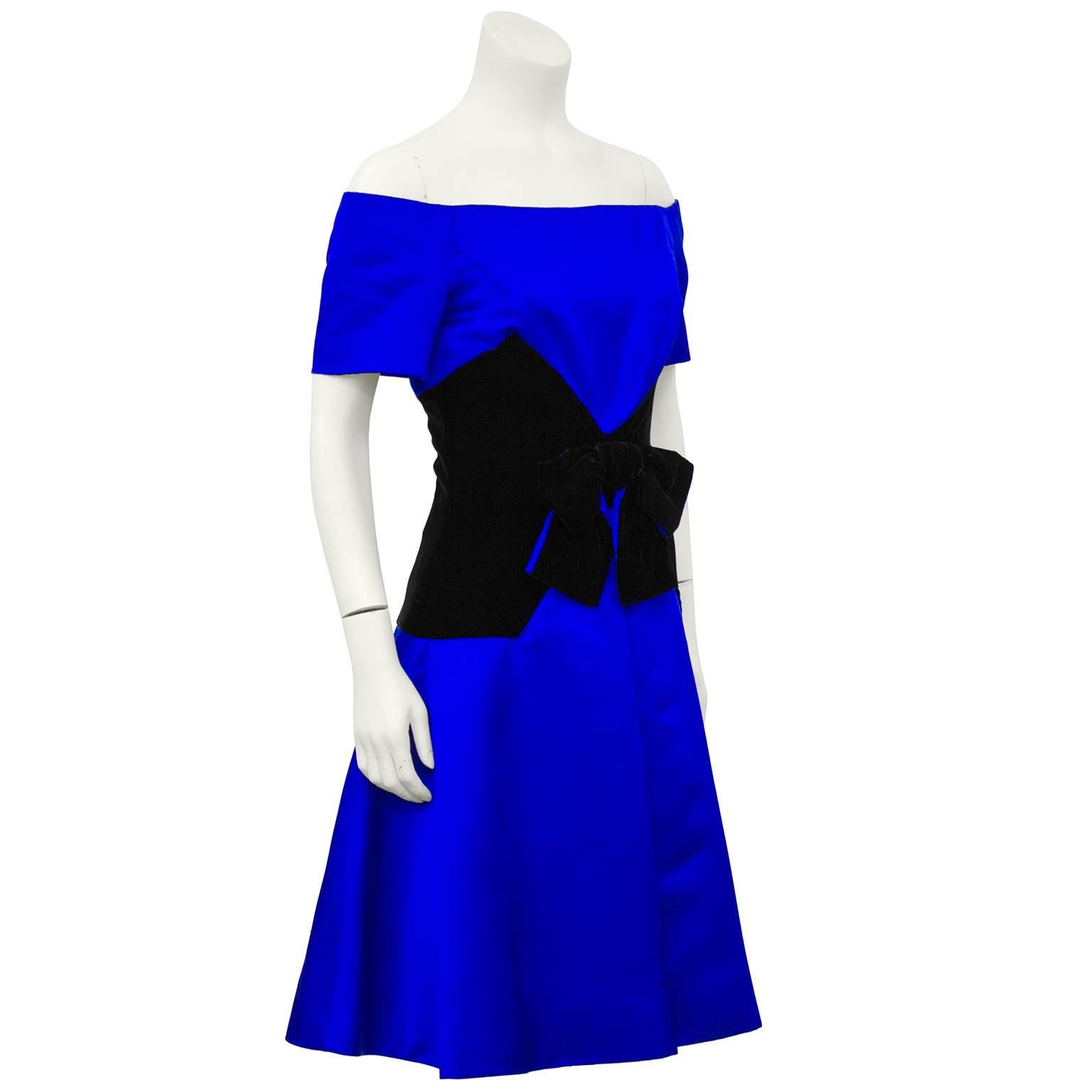 Stunning Scaasi cocktail dress dating from the 1980s. Royal blue satin with a jet black velvet wide corset waistband, featuring a very typical Scaasi large bow. Off-the-shoulder with short sleeves. Excellent like new vintage condition. Fits like a
