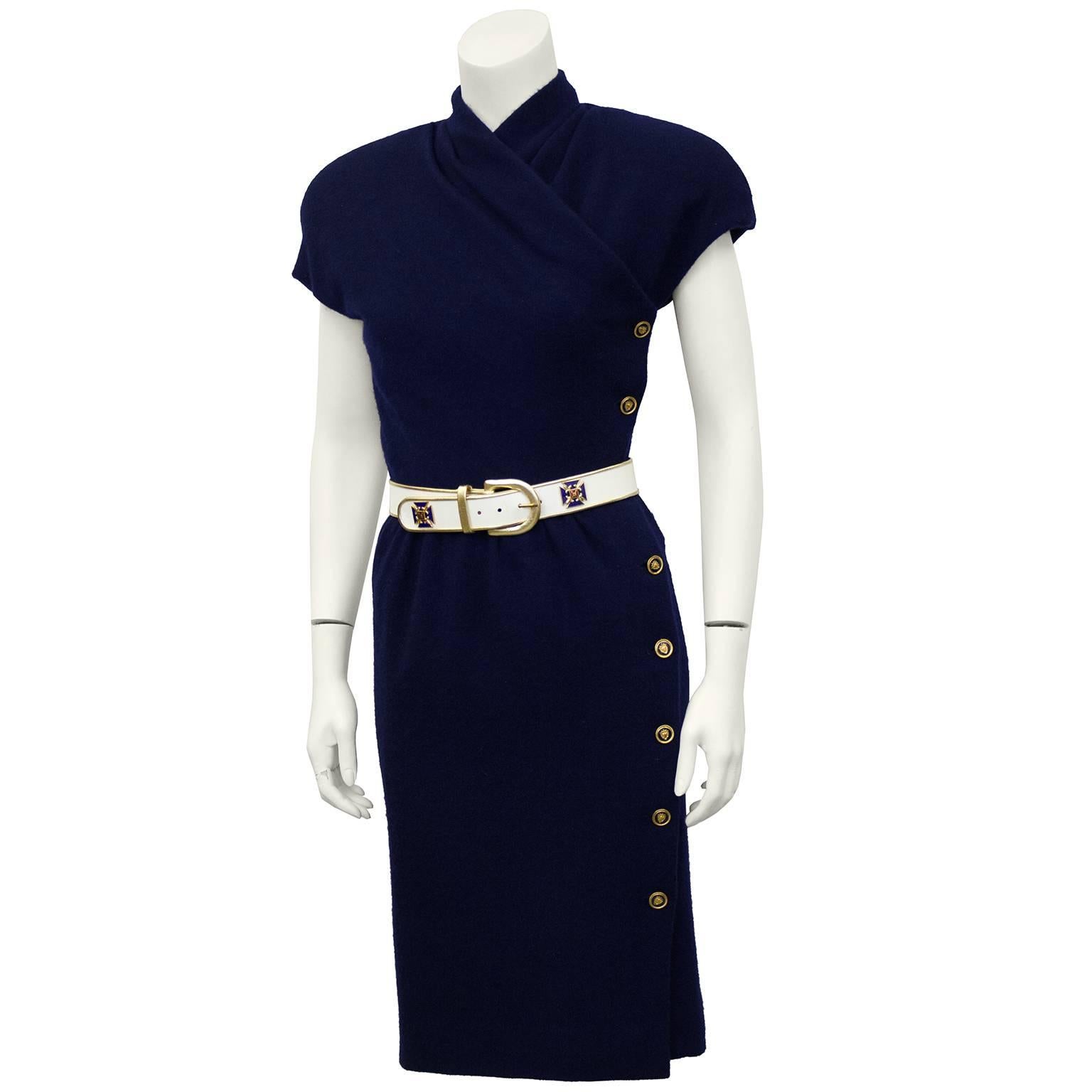 1980's Carolyne Roehm navy blue wool short sleeve faux wrap style dress. Gold and blue crest buttons down left side of body. Matching white leather and gold belt with same crest as buttons. Shoulder pads can be removed. Excellent vintage condition.
