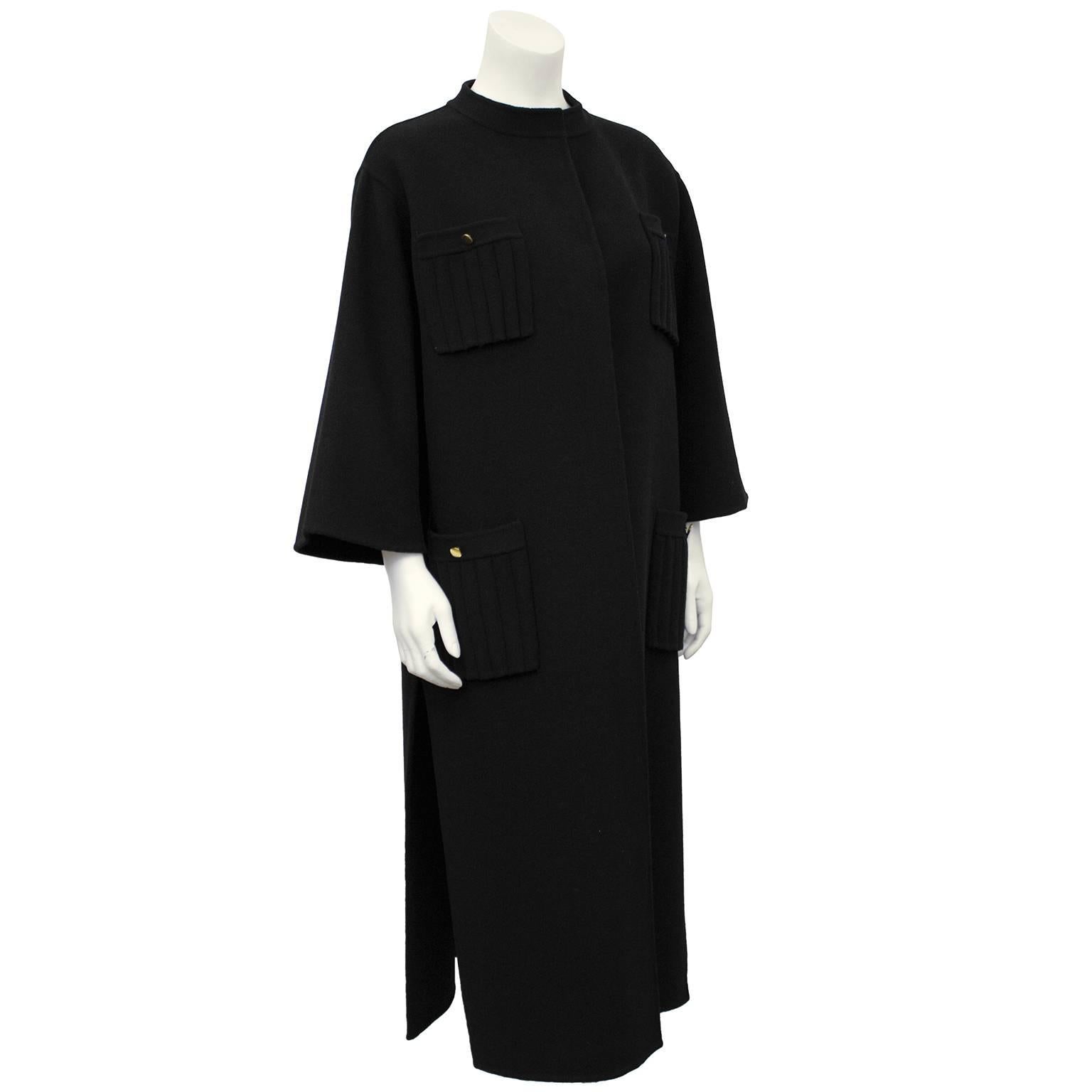 Beautiful unlined black felted wool coat dating from the 1970's. Four ribbed patch pockets on hips and lower bust with gold button details. Sits open on the body, with no buttons down front. Elegant openings  up both left and right sides seams.