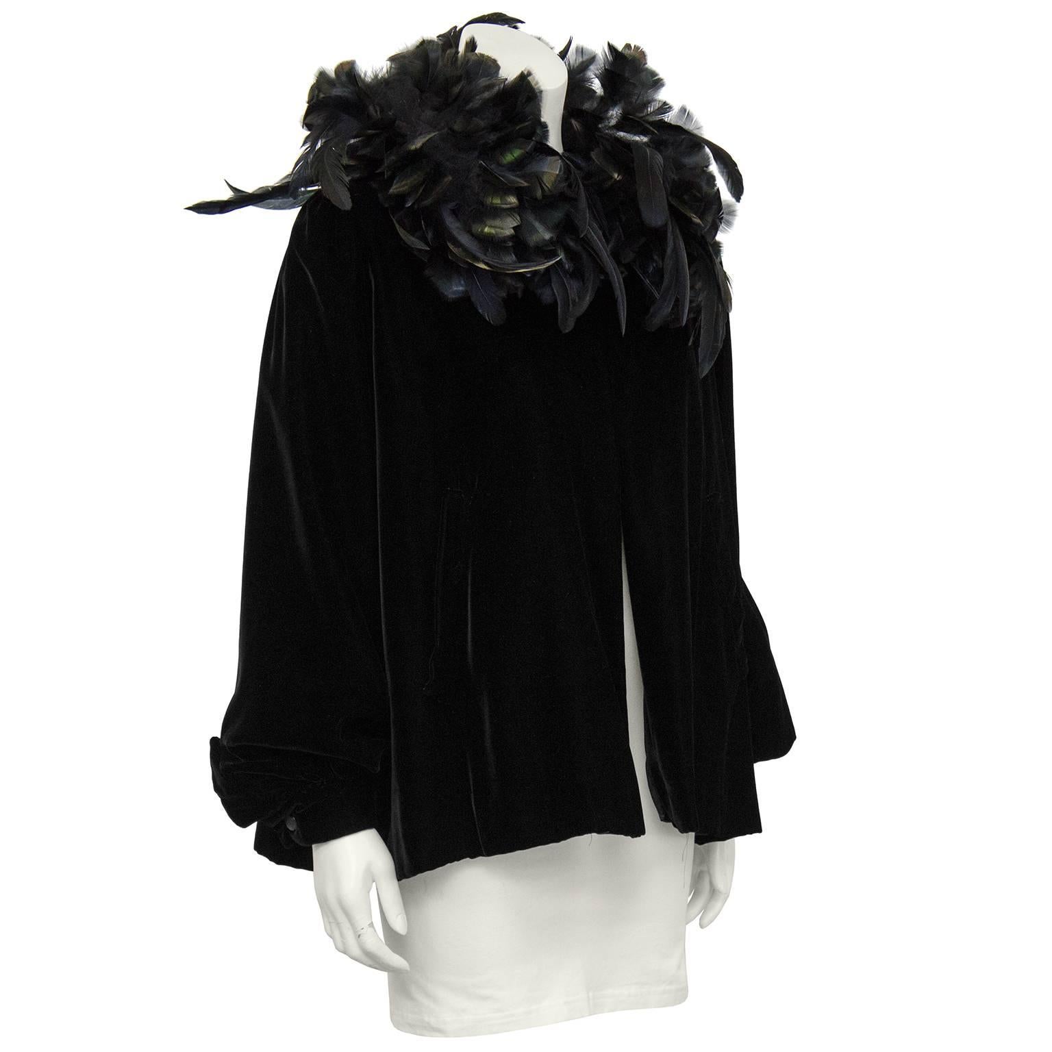 Show stopping and stunning early 1980's Yves Saint Laurent jet black velvet swing jacket. Decorated with a neck full of beautiful black feathers with shades of blue and green when light hits. One large hook and eye closure at neck to allow the