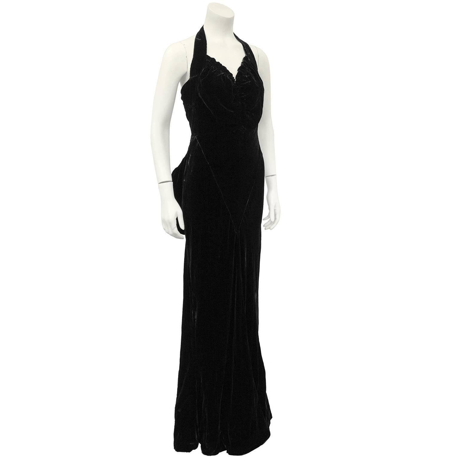 Incredible 1930's jet black velvet Chanel Haute Couture gown. Halter neckline with ruching throughout bust. Fitted through bust and skim the waist and hips, with a very slight mermaid skirt and very small train. Oversized bow at back, under button