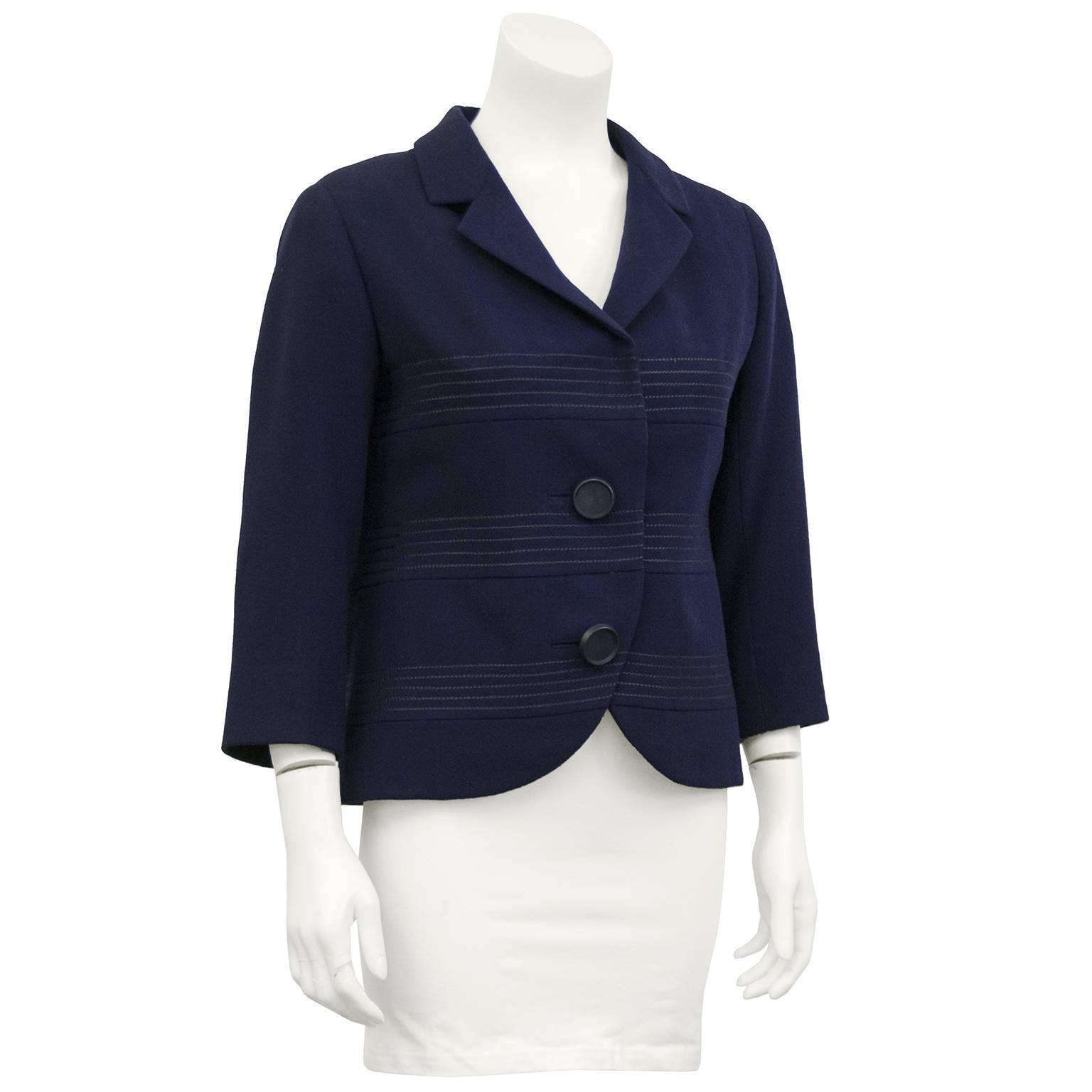 Christian Dior Original label Navy wool cropped jacket from the 1960s. Notched collar lapel with banded detail across the body. Two large navy buttons up the front with hidden hooks to secure closure. 3/4 length sleeves and cutaway detail at the