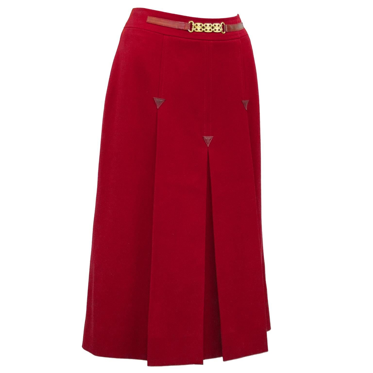 1970's Celine red wool skirt with leather details and gold link buckle. Inverted box pleats on the front and back with red leather triangle appliques. Gold link faux buckle on the waistband secured with leather tabs. Overall A line shape. In