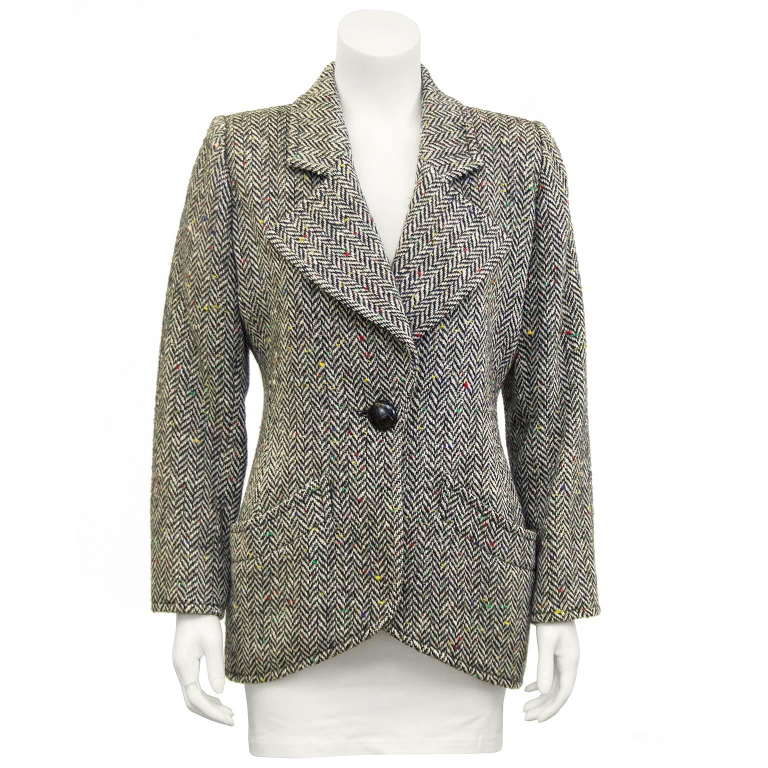 Yves Saint Laurent jacket dating from the 1980s. Black and white herringbone wool with yellow, red, green, and blue specks throughout. Equestrian style with large faux weaved black button. Domed black plastic buttons at cuffs and diagonally cut slit