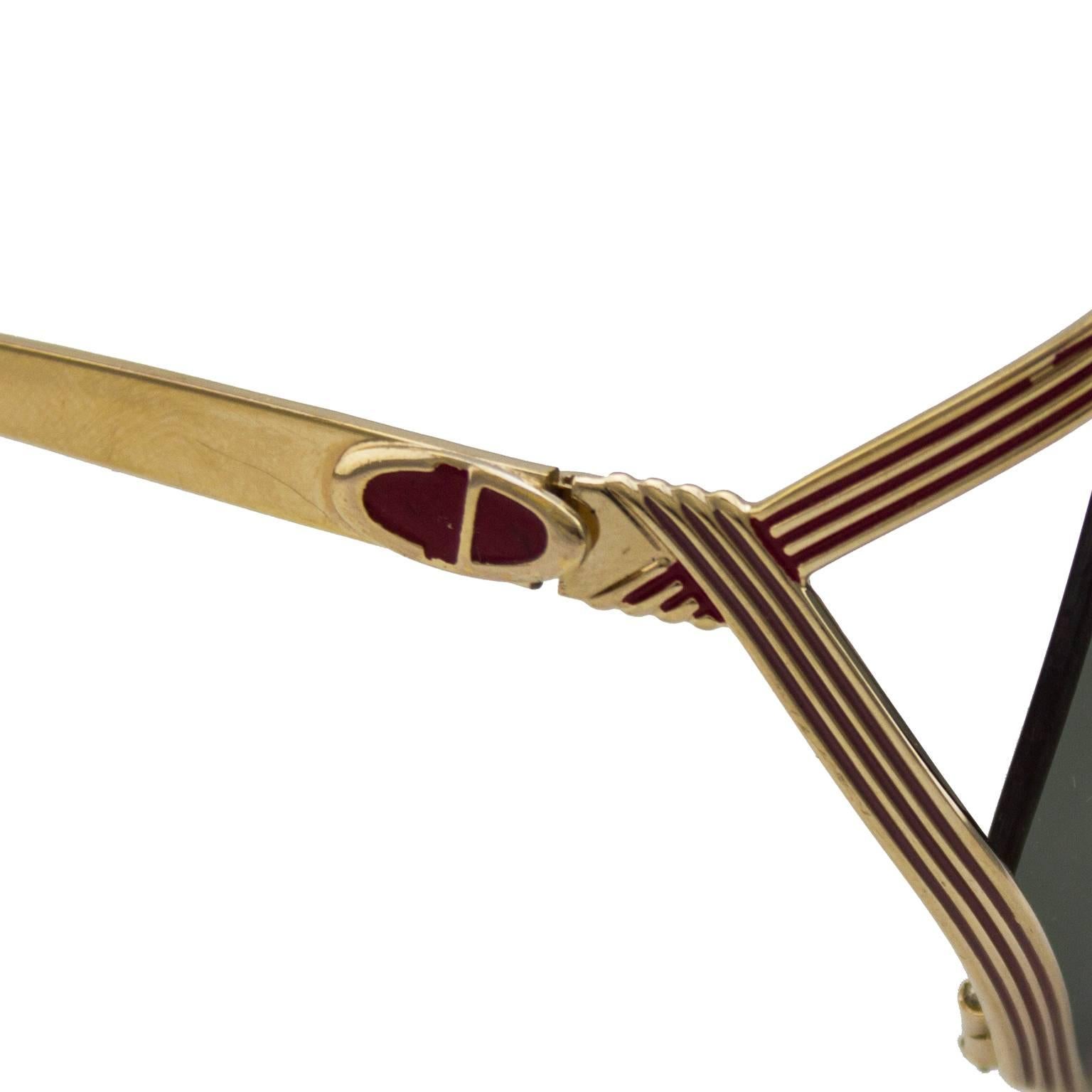 1980s Christian Dior gold metal sunglasses with red details throughout. CD logo on both arms and brand engraving on interior arm. New dark grey lenses. Excellent vintage condition. No box or case. 