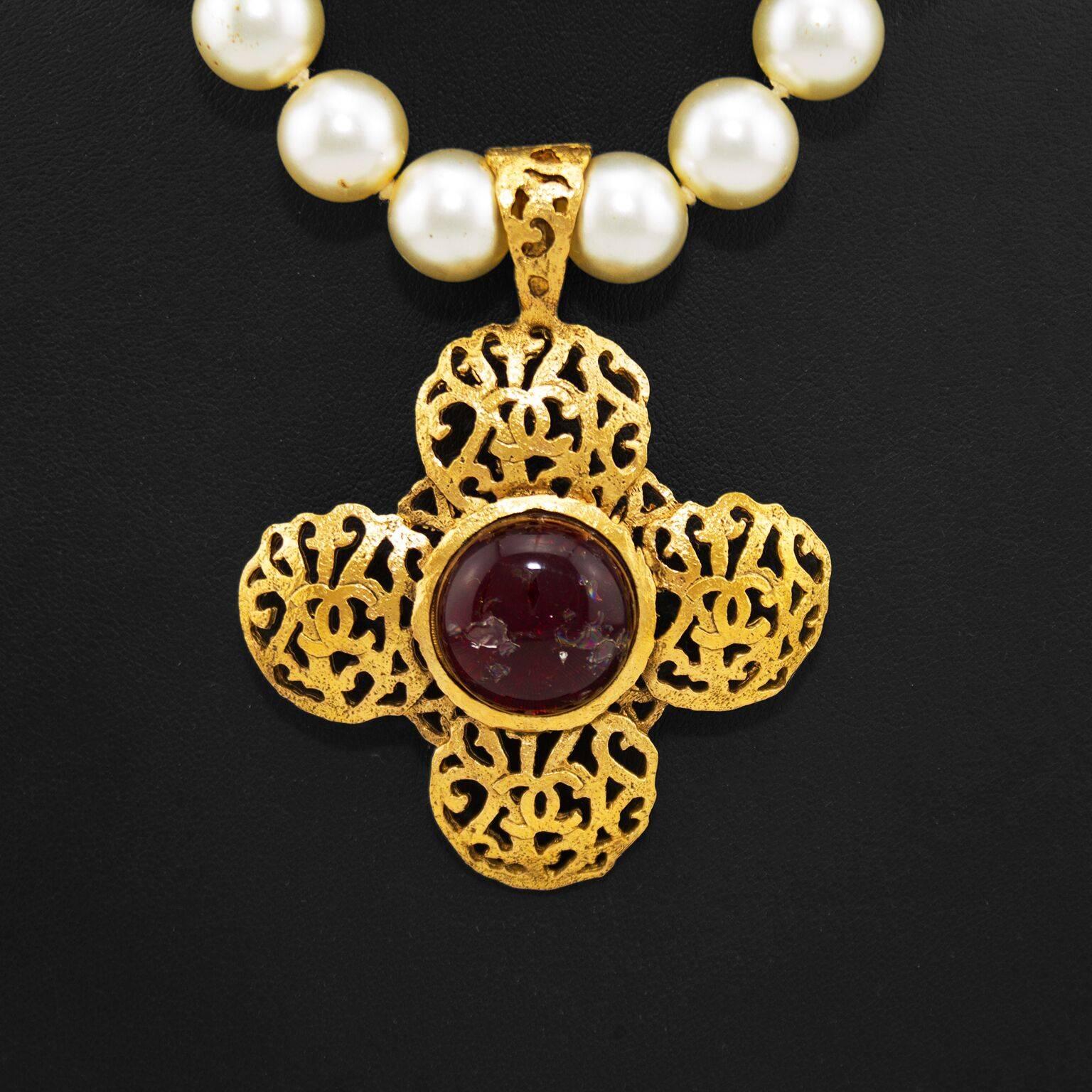1970s Chanel faux pearl necklace with a large gold tone filagree pendant with CC logos added into the filagree design. Centre of the pendant is dark red crackle effect poured glass. Gold tone lobster clasp  and dangling CC logo at nape of neck. In