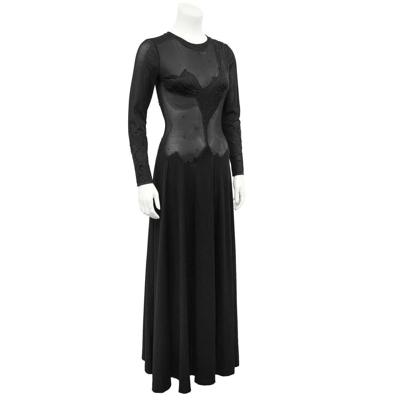 Stunning early 1970s Giorgio Di Sant’Angelo black illusion gown. Stretch lycra long sleeve, sheer bodice with hand floral beading and rhinestones. Key hole detail at nape of neck with a button closure. Full skirt starts at hips. Perfect red carpet