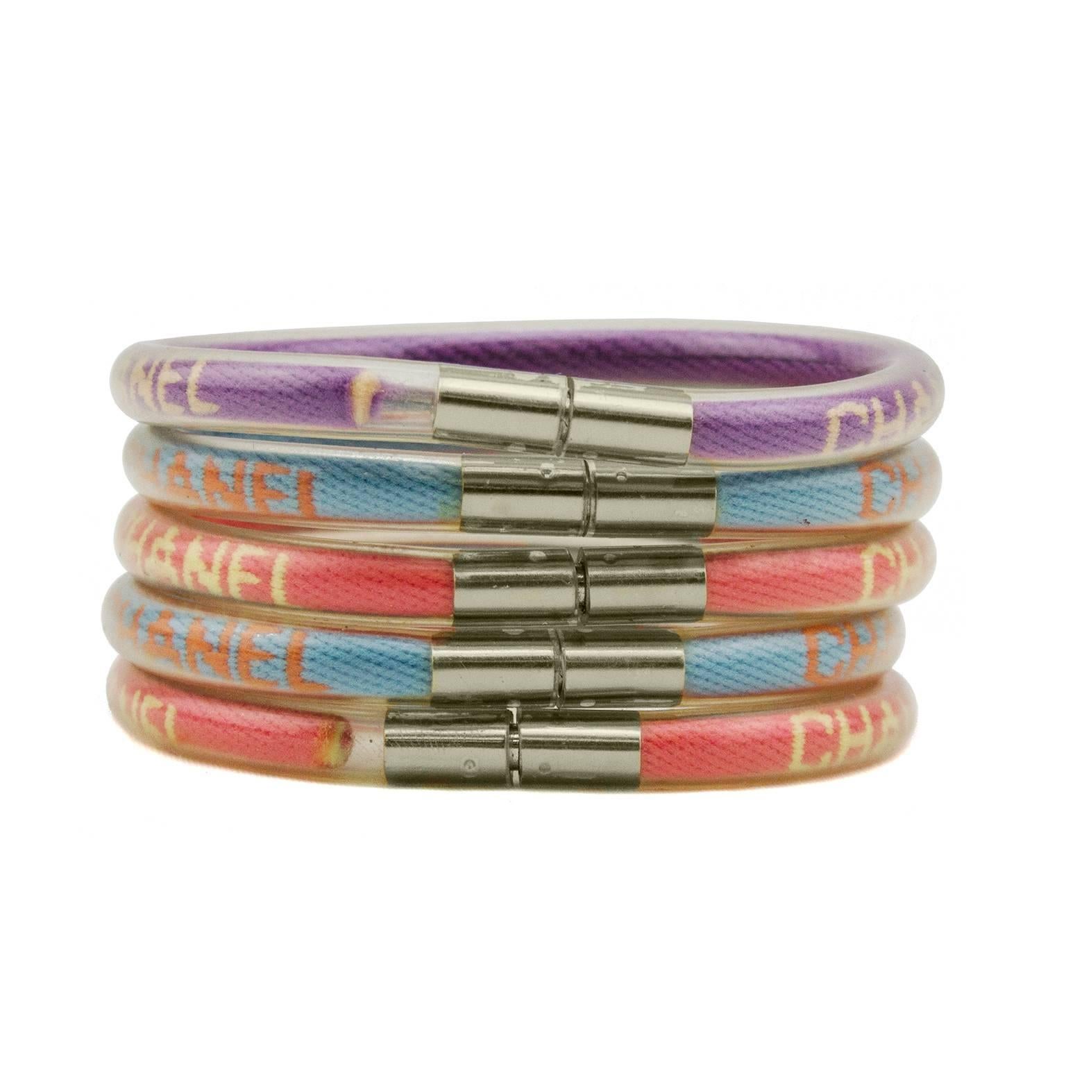 Super cute set Chanel bracelets from 2000. Five bright mutli color woven bracelets incapsulated in transparent PVC with silver hardware. Magnetic tube clasp. Small silver Chanel brand markings on interior. Two blue, two coral and one purple. Can be