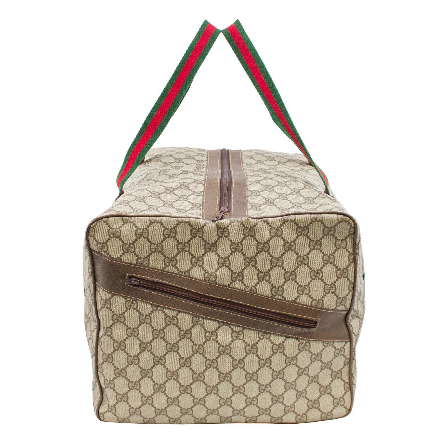 1970s Gucci coated canvas monogram overnight/duffel bag. Iconic green and red striped straps continue down the sides of the bags and underneath. Trimmed in brown leather with top zipper and one exterior zipper pocket on the side. In very good