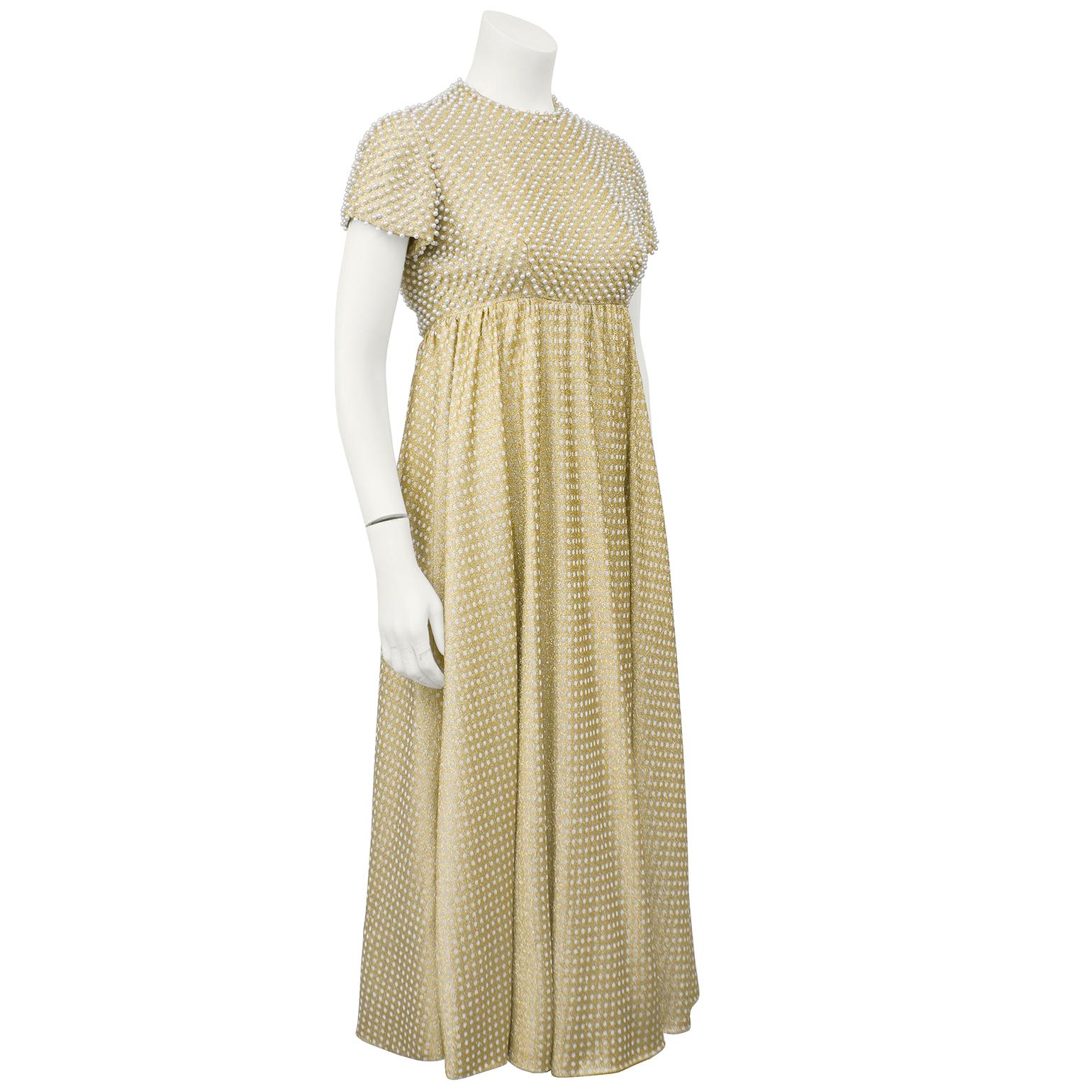 Stunning 1970's gold and white metallic knit maxi dress studded with pearls on the bodice. Capped sleeve, empire waist and flaired skirt combine well to highlight almost any figure. Currently ankle length. In fresh clean and ready to wear condition.