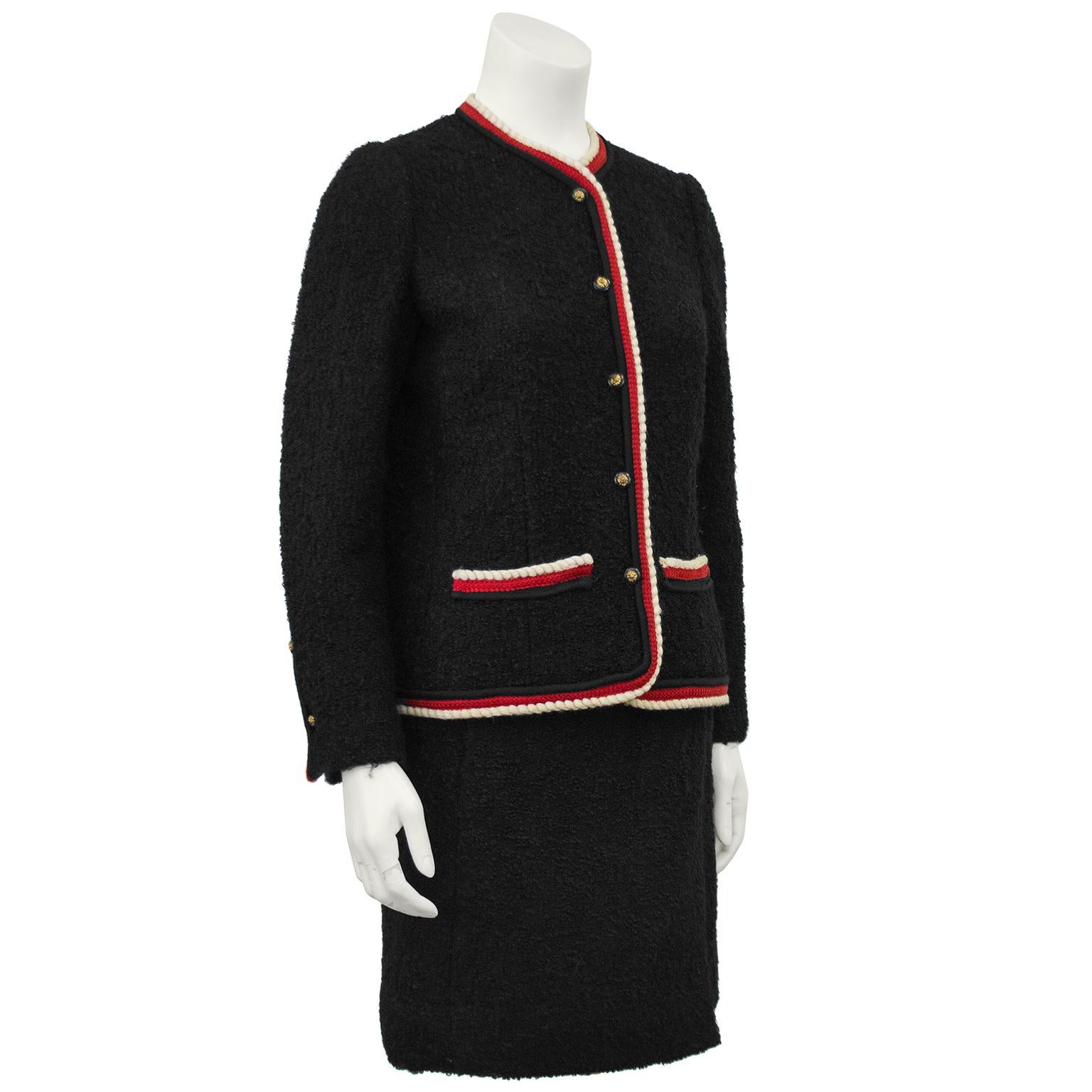 The very best example of Chanel's classic ladies suiting. Black wool boucle with red and cream trim and the most appealing black buttons with lions head in gilded metal. Simple, tasteful and a lifelong friend. Every closet deserves this timeless