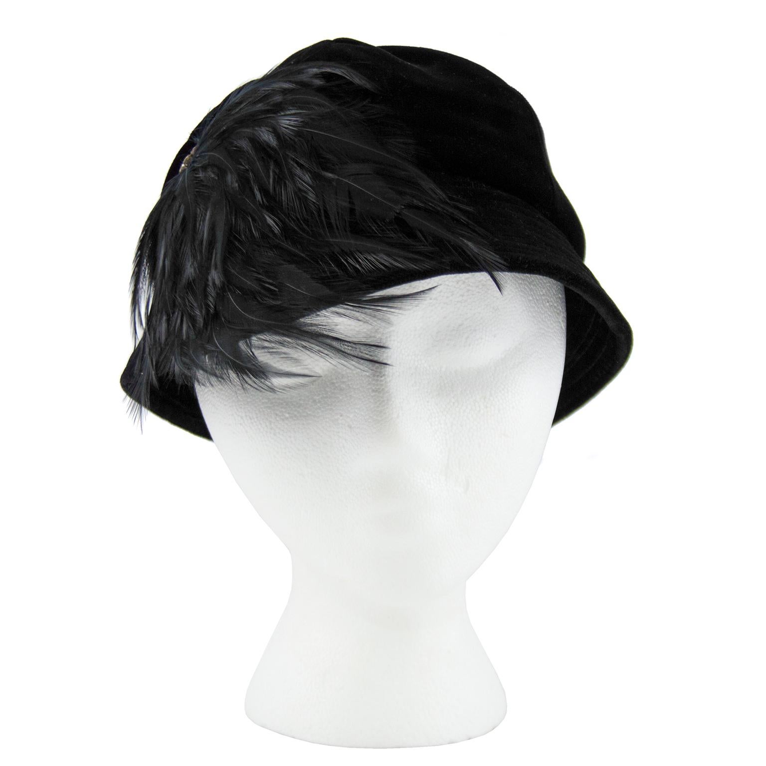 1950's black velvet cloche style hat with dramatic feathered detail and rhinestone circular ornament. In excellent condition, meant to beworn on a rakish tilt for the best effect!  Interior circumference 21
