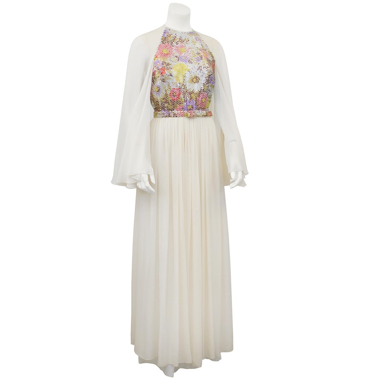 Look like a disco butterfly in this beautiful white chiffon gown with floral sequin bodice. The  gown is actually sleeveless and the chiffon sleeves, that are open on the underside, flutter away from the body. The waist is cinched with a matching