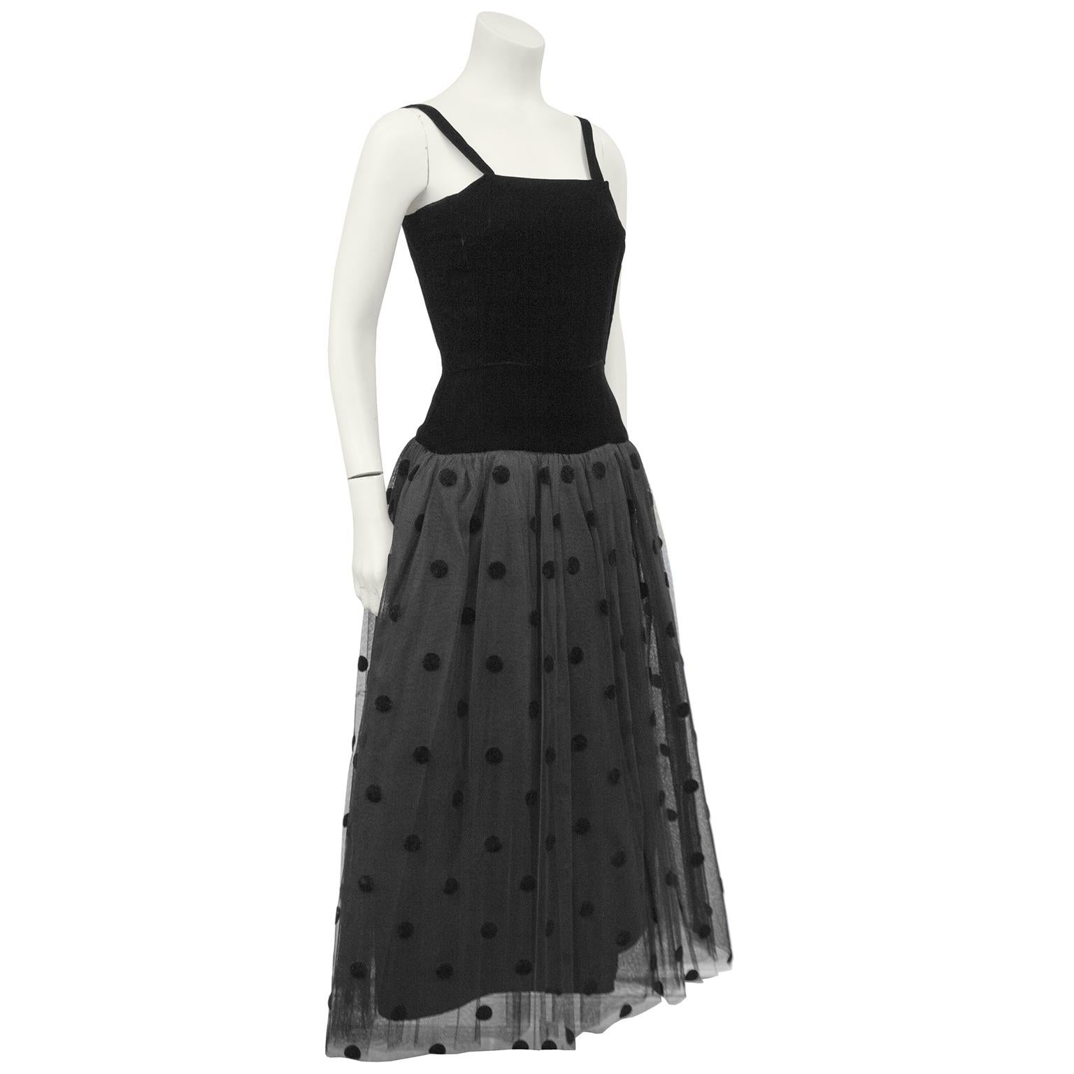 Anonymous 1980s black velvet drop waist dress with tulle skirt. The bodice has black shoulder straps and darts at the bust. Fitted through the body, the drop waist tulle skirt has black velvet polka dots throughout the top layer with 3 tulle layers