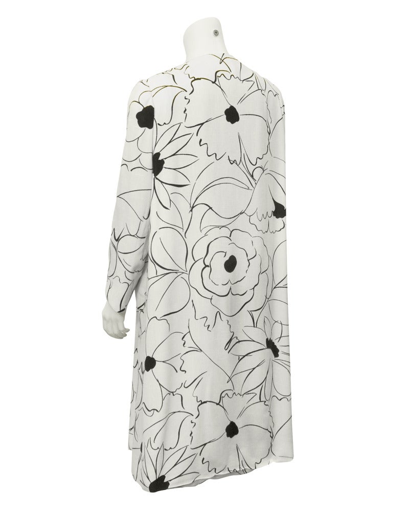 Early Nina Ricci piece, dating from the 1960's. Coat is white linen with a gorgeous print of outlined flowers in black. Floral print has a loose quality, looks as though it was sketched on the coat. Coat features bracelet length sleeves, seven