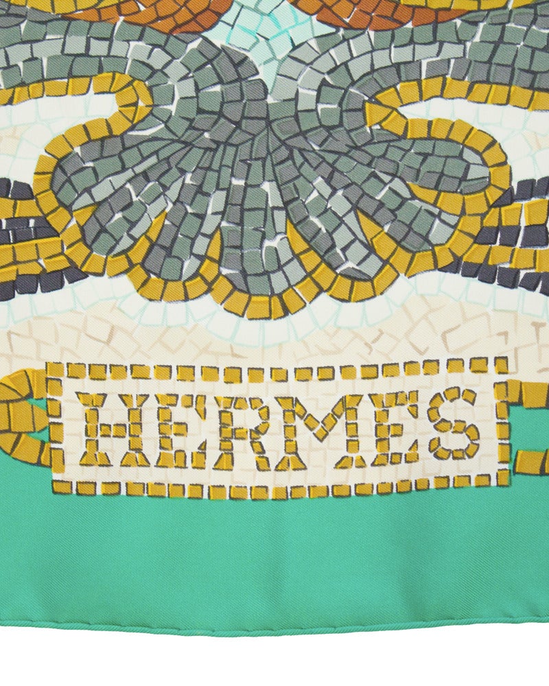 Bright and beautiful silk hermes scarf dating from 1991. Scarf features a mosaic of cream, gold, grey and blue tiles creating a nautical/aquatic inspired mural with a deep turquoise boarder. Hand stitched rolled edge finish with all Hermes markings.