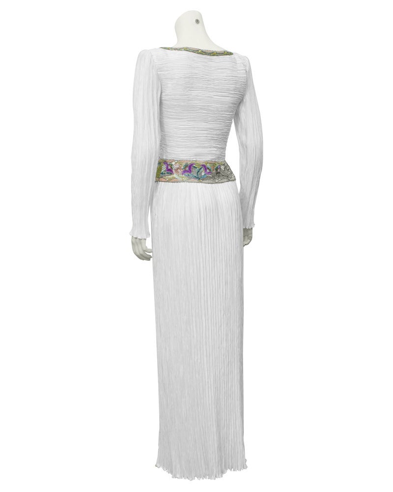 Long sleeve white Mary McFadden gown from the 1970's. The gown is created in the iconic and instantly recognizable Mary McFadden Marii pleating. The bodice and neckline are embellished with a multi colored beaded floral motif. This gown is