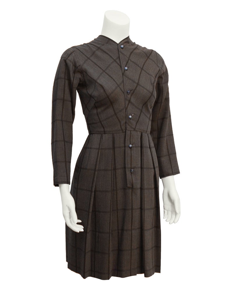 Impeccably tailored 1950's Claire McCardell day dress. Brown wool with a chocolate brown and grey argyle and plaid throughout. Day dress features a raise neck line with buttons down the front and bracelet length sleeve. Skirt is full with inverted