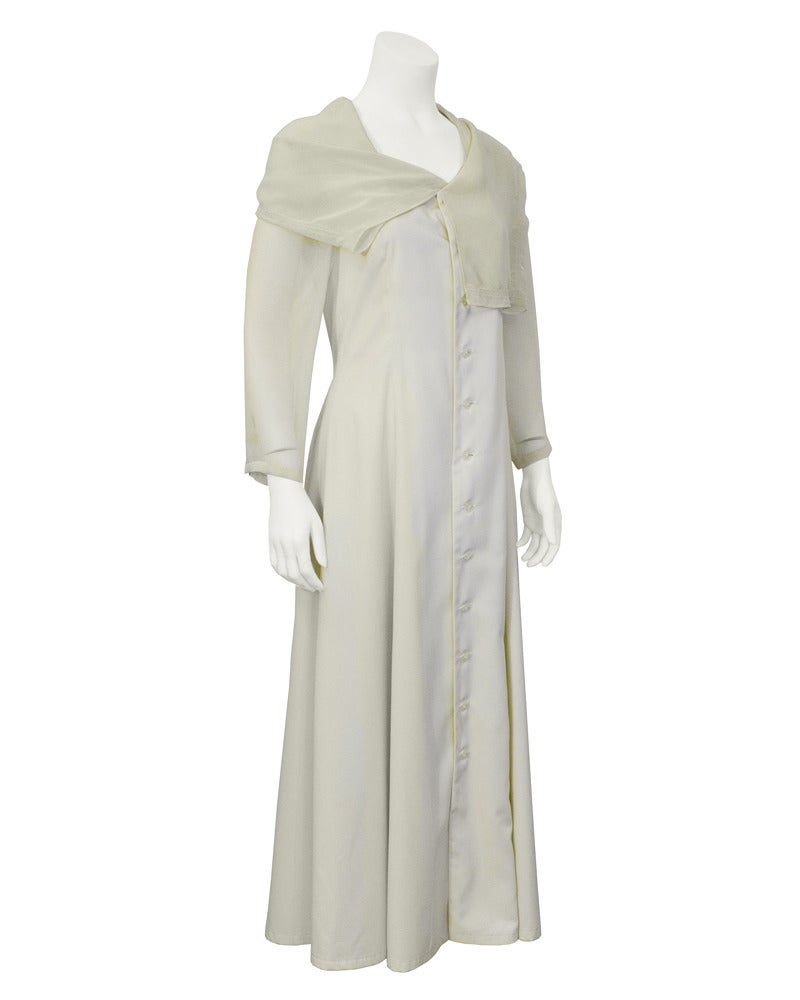 Interesting 1990's piece from Japanese brand Matsuda. Cream colored silk coat dress with buttons all the way up the front, asymmetrical pleating through the back of the skirt, silk chiffon sleeves and a silk chiffon shoulder overlay. Excellent