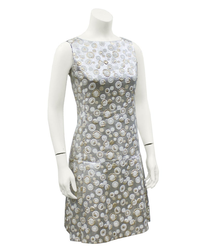 Cute silver, white and gold Malcolm Charles brocade dress from the 1970's. Sleeveless and drop waist with a wide box pleat skirt. Mod style polka dot pattern throughout the brocade. Excellent vintage condition. Contemporary feeling with a touch of
