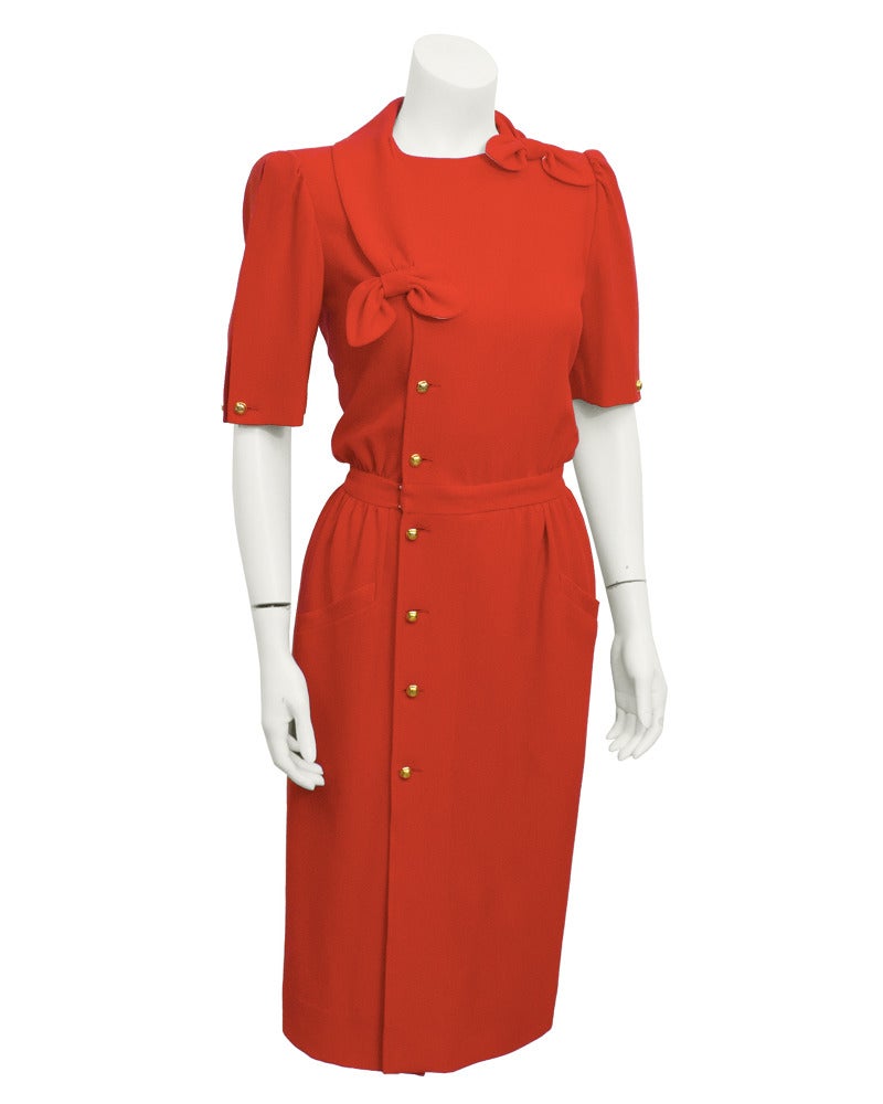 1980's Valentino day dress with cinched waist and bow details at neck. Gold buttons closures down the right side (when wearing) and short sleeves with gold chain cuff links. Great shape and wonderful color. Everyone needs 1 red Valentino for their