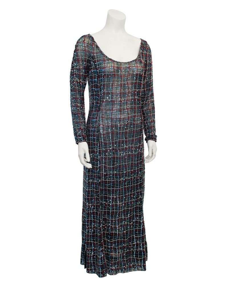Stunningly intricate 1990's Armani diaphanous hand beaded gown. Boat neck, long sleeve with a tasteful slide slit. Gauze netting black gown skims the body and is completely covered in red, blue, green and white bead work forming a free hand plaid