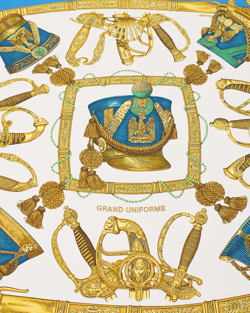 Bright blue, white and gold Hermes 'Grand Uniforme' silk scarf. Date of issue is 1985. Military theme of helmets and swords designed by artist Joachim Metz. Hand rolled edges, Hermes markings. Excellent vintage condition. Beautiful scarf.