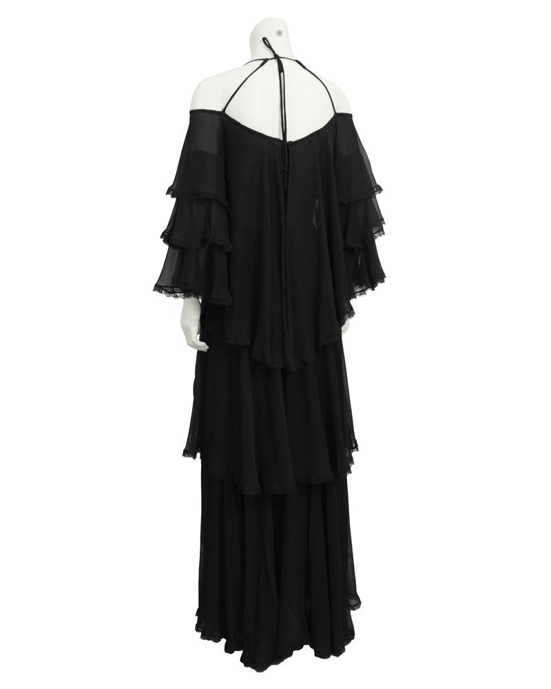 Attributed to Dior. Stunning 1960's black silk chiffon multi-tiered gown. Tiers are trimmed thinly in black lace. Gown has off the shoulder sleeves and with two spaghetti straps that tie at nape of neck. Fashion forward and sexy. No label, however