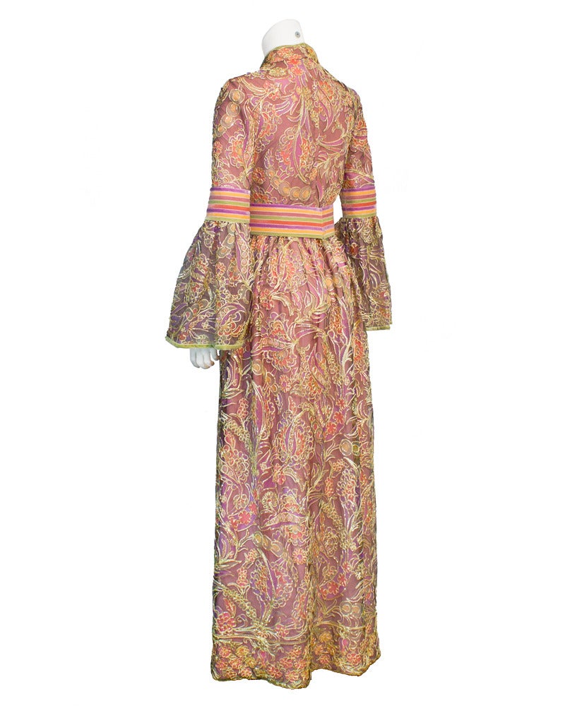 The ultimate boho gown for the festive fashionista from the 1970's. The gown has a slight high collar accented with a slit neckline, bell sleeves and the skirt falls from the natural waist. The beautifully crafted fabric is made up of a purple
