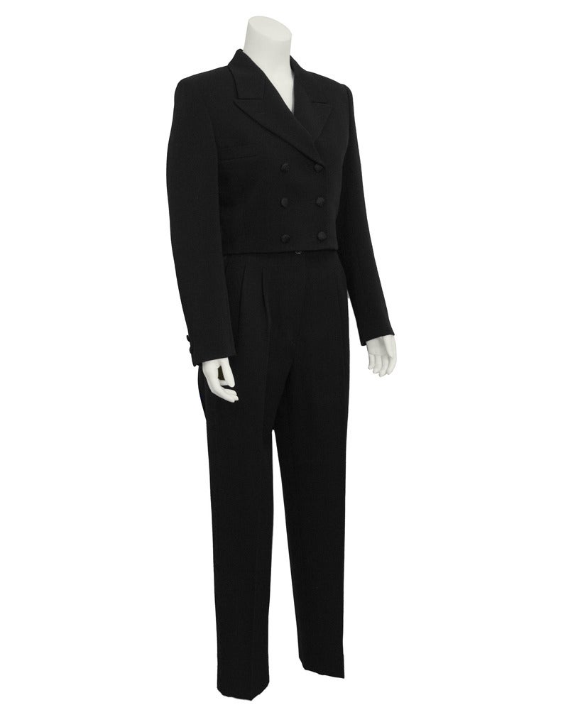 1988 black wool Comme des Garcons tuxedo pant suit. Double breasted jacket is cropped at the waist with half detached tails at the back. Buttons on jacket are covered in a beautiful silk jacquard. Pants are cropped at the ankle with a satin trim