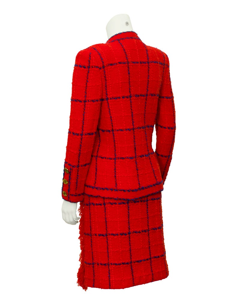 1970's classic red Adolfo knit suit with navy window pane pattern and adorable fringed edges. Over sized gold plated buttons trim the cuffs of the jacket and decorate the front of the skirt. Lots of give in this wool knit ensemble. Even the former