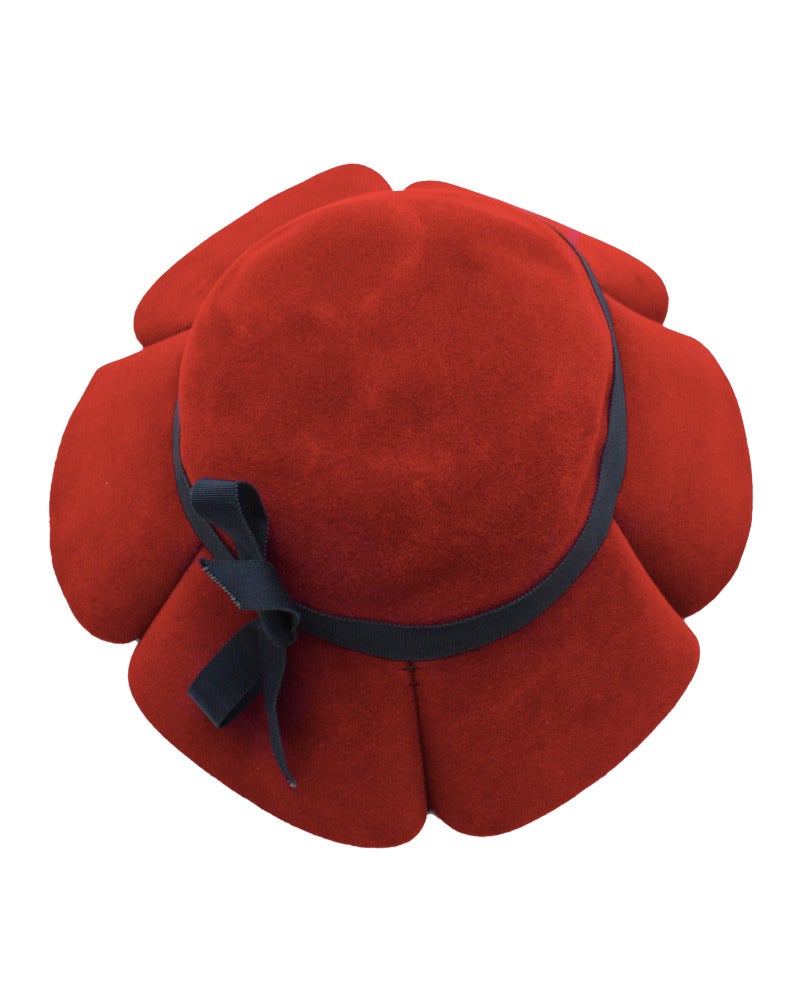 Red felt Lilly Dache hat dating from the late 1950's. Hat flares out with inverted pleats. Thin black grosgrain ribbon with bow detail is hand tied. In excellent condition, very visual inverted pleat design.