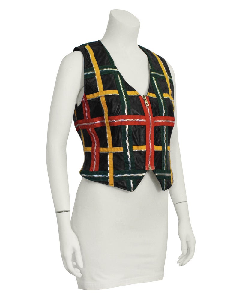 Fun and funky 1980's Moschino leather vest with over sewn decorative zippers. Vest is black crinkled leather with green, red, yellow and silver zippers applied into a windowpane/lattice pattern. One red zipper down the center front functions as the