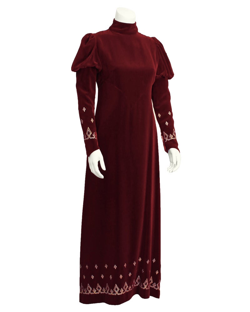 1970's burgundy velvet mock turtleneck, long sleeve gown. Mutton style sleeve at shoulder, tapers and elongates past the wrist forming a point. Very Directoire inspired 70's London Look piece. Bottom of sleeves and bottom of skirt are decorated with