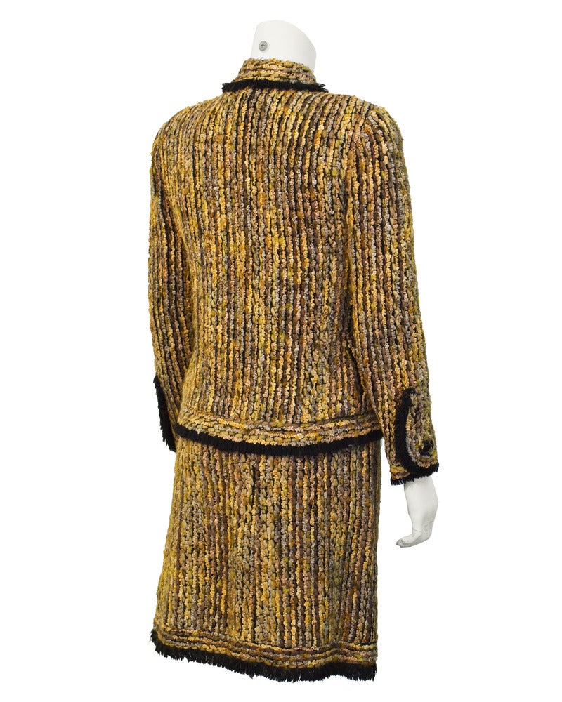 1970's Chanel Haute Couture suit. Uniquely Chanel in appearance, with black wool fringe surrounding the edges of the jacket, pockets and skirt hem. Gold chain and 3 gold metal Chanel weights inside the lining of the jacket plus the faux tortoise