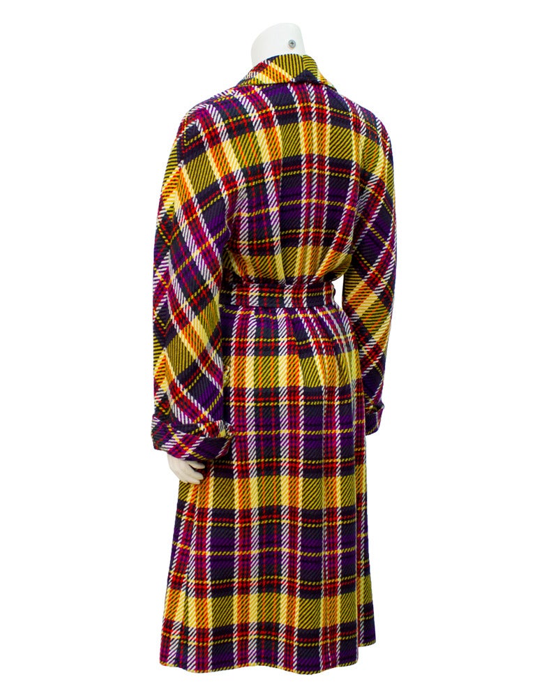 Purple, yellow and red tartan trench style wool coat by Valentino from the 1970's. The coat features masculine details like a wide notched lapel, double breasted buttons, rolled cuffs, top flap pockets at the hips and a matching belt that ties at