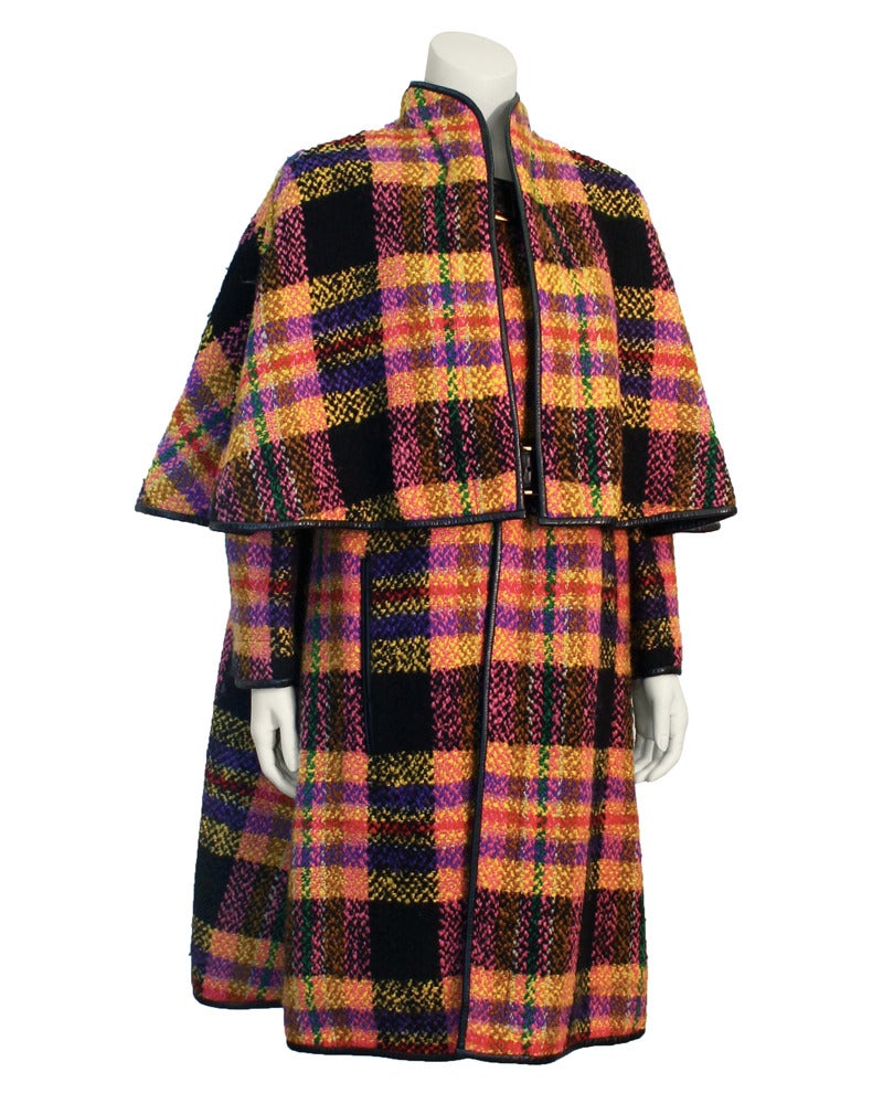 Late 1960's Bonnie Cashin plaid cape with tones of pink, purple, red, black, brown, yellow and green. Trimmed in black leather with large black leather and gold tone metal buckles. Great combination and use of color. Stunning piece, in excellent