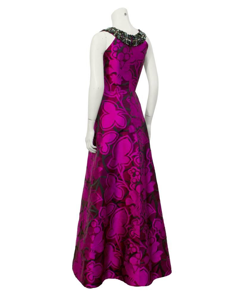 Stunning tyrian purple silk gown with an abstract floral pattern in black and a dark magenta color. Form fitting bodice with a-line skirt. Neckline has black, pewter, pink and purple crystal embellishments that are lined with black piping. The gown
