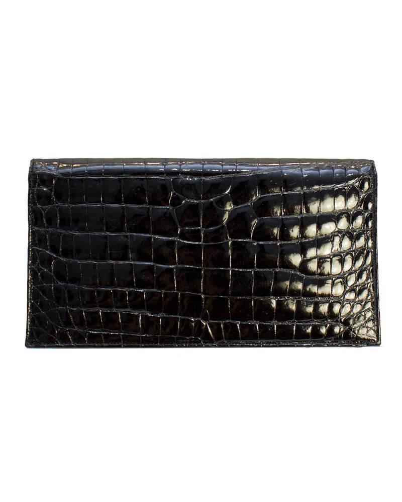 1950's Lucille De Paris black crocodile mini clutch with bow detail on front flap. Bag has black leather and satin interior with one open interior pocket and original compact mirror. Excellent vintage condition.