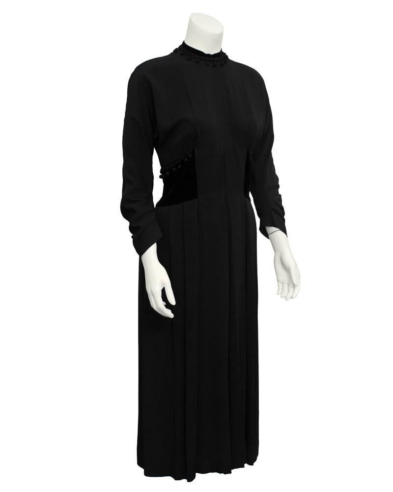 Late 1940's Hattie Carnegie crepe dress with pom pom and jet black velvet details at the waist and mock turtleneck neckline. 3/4 length dolman sleeves with gathered and softly pleated skirt. Excellent vintage condition. 