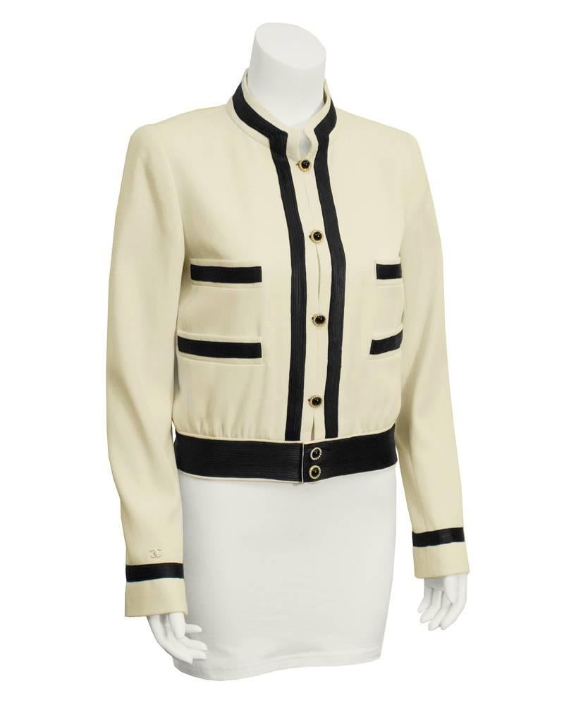 Cream wool Spring 2002 Chanel jacket with black satin trim, military styling and elegant faux pearl, gold plate, and black dome cuff link style buttons. Dressy enough to wear over a black cocktail dress, silk tuxedo pants or with your favorite pair