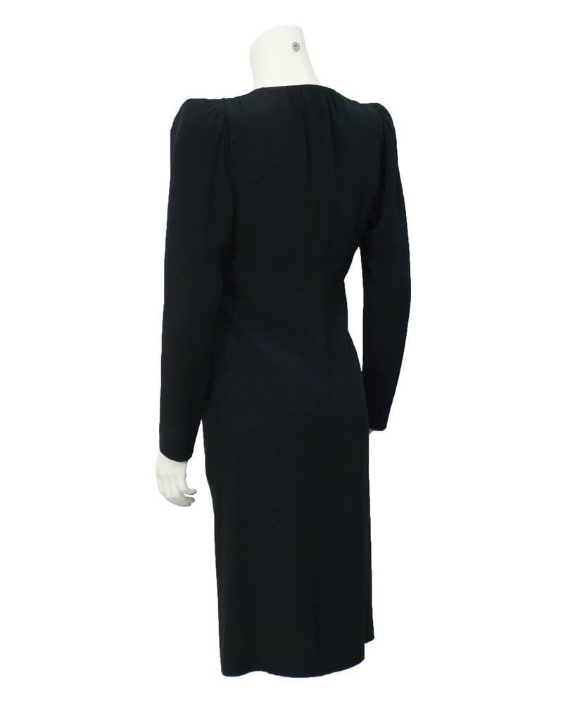 YSL 1980's slinky black silk crepe V-neck cocktail dress with front zip trimmed in single row of rhinestones. A slight gathering to the front adds interest to the form fitting shape. Shoulders are classic though not over exaggerated YSL squared off