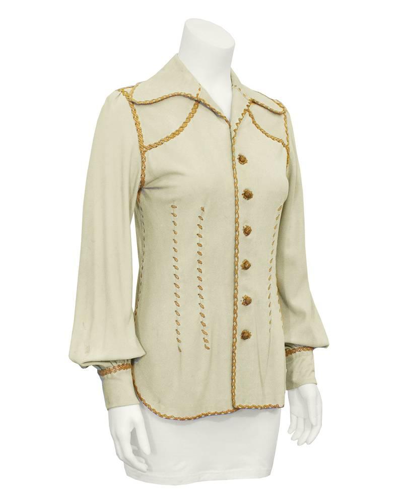 Rock'n'roll 1970's North Beach Leather beige chamoix blouse. Detailed with tan leather whip stitching throughout hem and seams. Leather woven sphere buttons. Marking where the North Beach Leather label used to be. Good vintage condition, slight