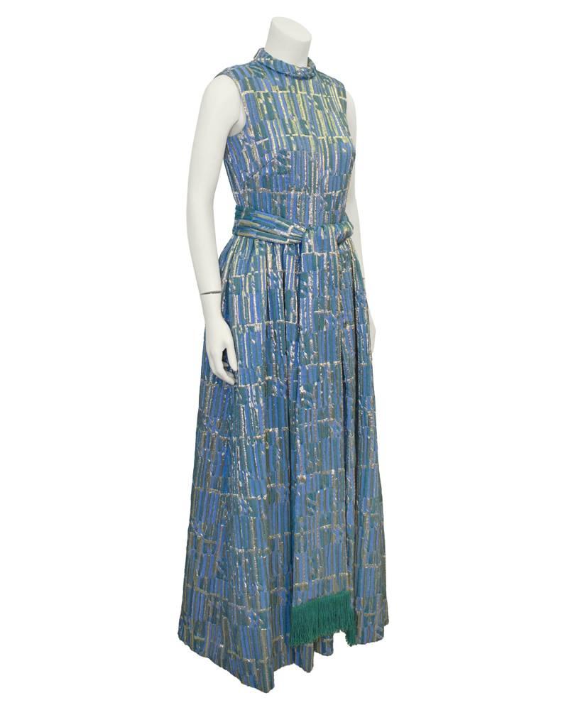 Stunning 1960's periwinkle blue, gold and turquoise green brocade gown and matching waist tie. Sleeveless with an elegant high rolled collar. Matching tie has great turquoise fringe at ends and snaps at waist to keep it in place. Inside green velvet