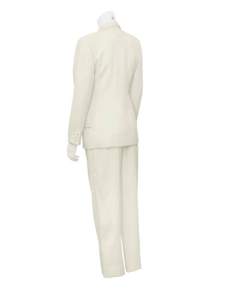 Amazing Dolce & Gabbana cream and white tuxedo from the early 1990s. The perfect mix of masculine and feminine, the tuxedo is made from a cream wool  crepe with white satin trim along the lapels, pockets, buttons and down the length of the pants.