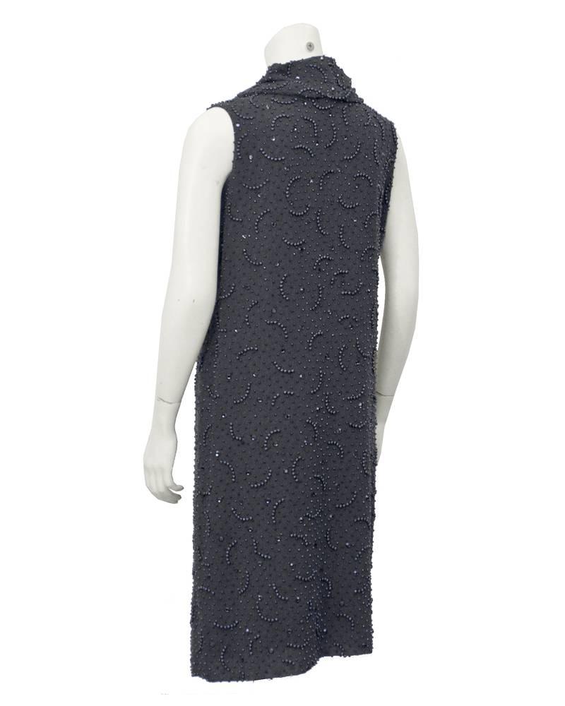 Great 1960's grey wool dress by Mr. John. Although best known as a hatmaker to the carriage trade even Mr. John had a hand at designing dresses for his clientelle. All over tonal grey beading with large grey rhinestones. Cowl neck is created by