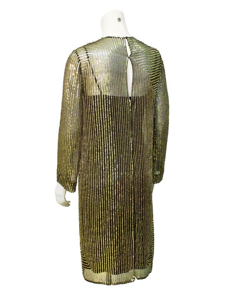 Gorgeous 1970's sheer long sleeve gold sequin cocktail dress with a black spaghetti strap slip underneath. Sequins form a square shaped pattern that shrinks in size with each row, leaving an small square that sits on the left hip. Invisible zipper