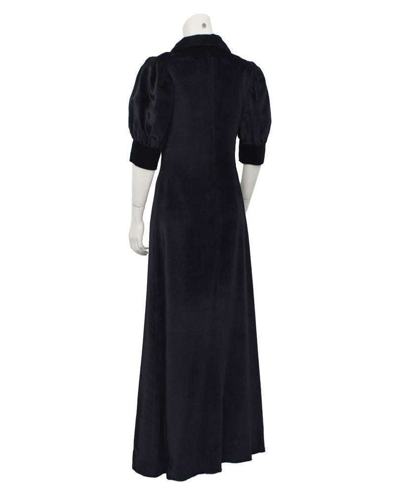 Atemberaubendes Kleid im Biba-Stil des britischen Labels Annacat aus schwarzem Pannesamt aus den späten 1960er Jahren mit hohem Sammlerwert. Weite, ellenbogenlange Ärmel, großer Kragen und Knöpfe auf der gesamten Vorderseite. Ausgezeichneter