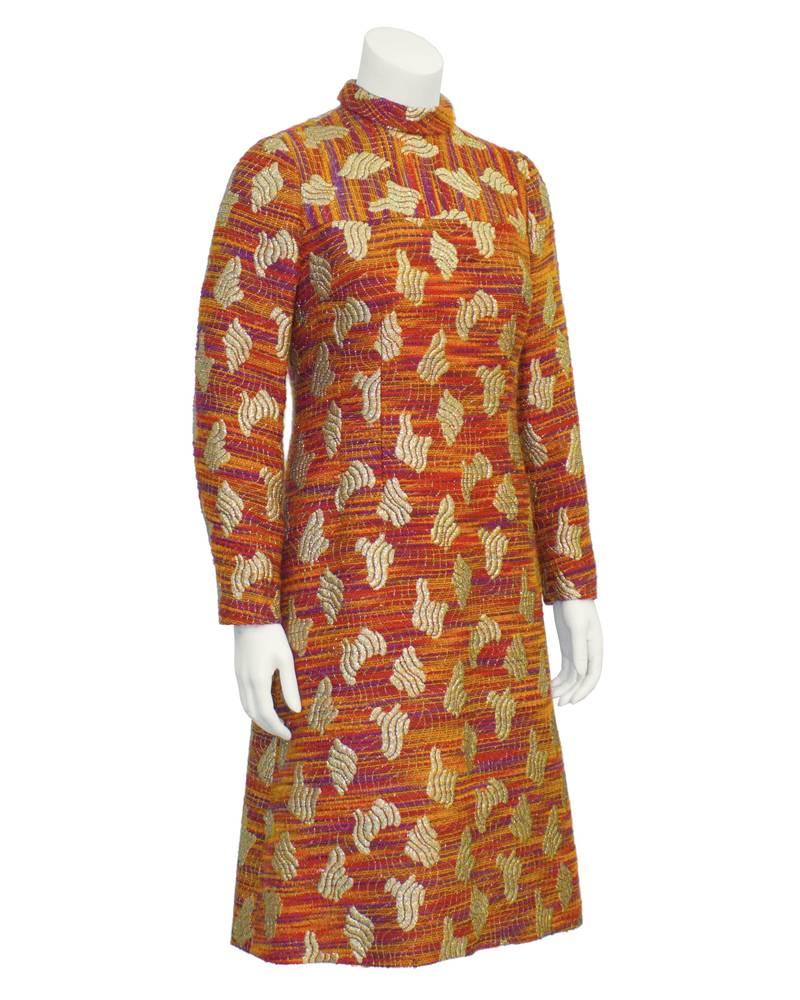 Beautiful A-line brocade dress from the 1960's. Covered in orange and gold pattern with notes of red and purple. Includes banded collar with long sleeves. Vertical seaming down front. Excellent vintage condition. Comes with optional matching belt