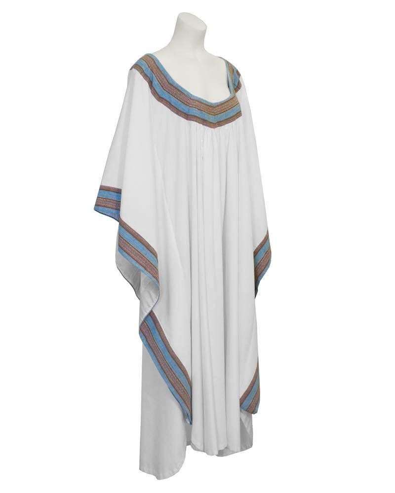 Fabulous white cotton kaftan from the 1970's. The neck and sleeves trimmed with with thick blue and brown woven tape. The perfect piece for a bohemian look. Very forgiving fit. Hard to find. Excellent vintage condition. Fits up to size 14 US.